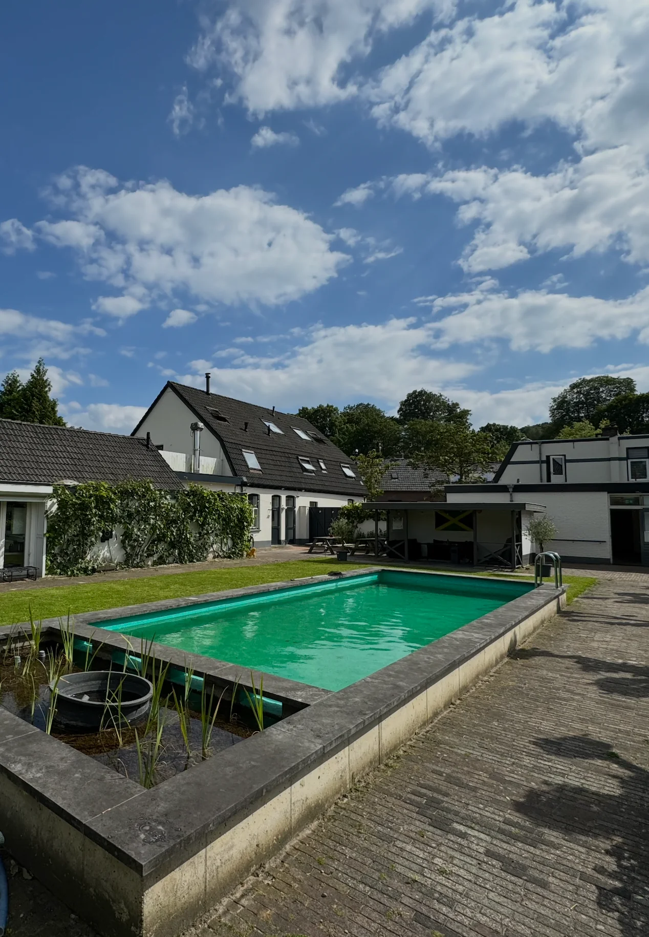 Het buitenzwembad in de tuin van De Verbinding, met de woonvorm op de achtergrond